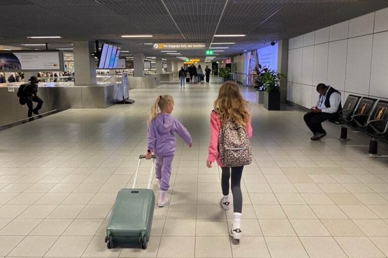 Koffer inpakken voor een vakantie met kinderen. 2 kinderen met koffer op vliegveld